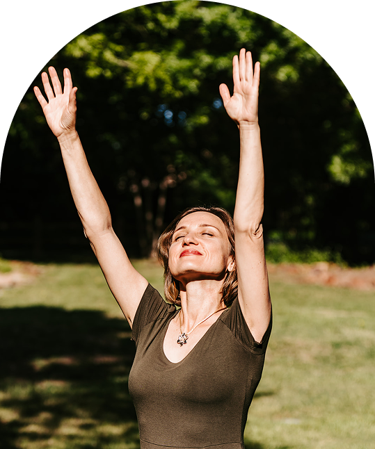 Lana Savit standing outdoors with arms raised, eyes closed, and a joyful expression, symbolizing holistic healing, empowerment, and alignment with nature.